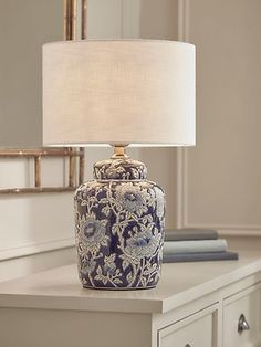 a blue and white vase sitting on top of a table next to a lamp shade