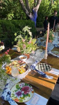 a long table with plates and flowers on it is set for an outdoor dinner party