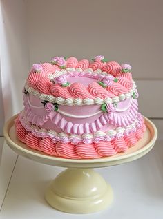 a pink and white cake sitting on top of a table