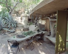 an outdoor dining area in the middle of a garden with lots of potted plants