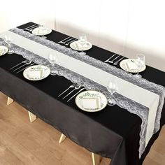 the table is set with white plates and black cloths, along with silverware