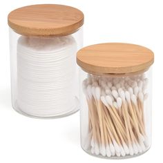 two glass jars with wooden lids filled with cotton swabs