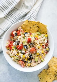 a white bowl filled with tuna salad next to tortilla chips