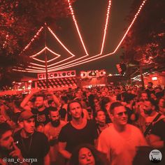 a large group of people standing in front of a building with lights on the ceiling