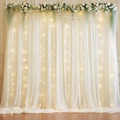 the curtain is decorated with flowers and greenery for a wedding or special event venue