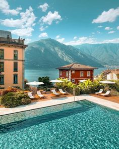 an outdoor swimming pool with chaise lounges and mountains in the background at grand hotel tremezzo - lake comoo