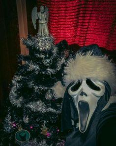 a person wearing a mask next to a christmas tree with a ghost face on it