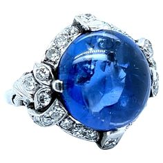 This outstanding antique ring is the embodiment of early 20th century glamour and sophistication. Center of the composition is a gorgeous, untreated, cabochon sapphire of approximate 15.20 carats. It is framed by refined platinum setting and 26 old-cut diamonds of approximately 0.80 carats, H/I colour and vs-si clarity. The ring is beautiful at first glance, but real magic lies in its depths - an entire galaxy seems to be contained within this beautifully mysterious piece. Maker’s Mark: HM Dimensions approx.: 20.00 mm x 20.00 mm / 0.78 in x 0.78 in Size: EU 53 / US 6.5 Weight: 10.64 gr. Sapphire: approx. 15.20 carats Cut: Round Diamonds: 26 diamonds, approx. 0.80 carats total Diamond colour/clarity: H-I / vs-si Cut: Old Real Magic, Maker’s Mark, Old Computers, Antique Ring, Shiny Things, I Love Jewelry, Antique Rings, Cocktail Rings, Early 20th Century