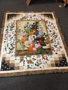 a quilted table topper with flowers on it and a chair in the background