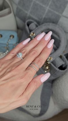 a woman's hand with pink manicured nails holding a diamond ring