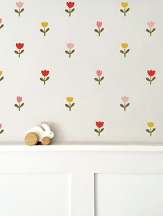 a wall with flowers painted on it and a wooden toy in front of the wall