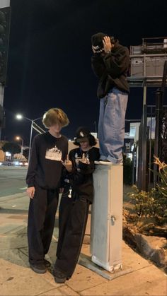 two young men standing on top of a metal box next to each other at night