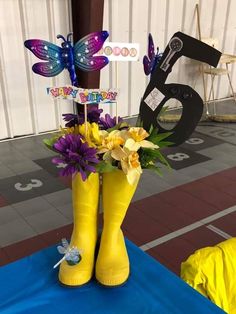 a yellow boot with flowers and butterflies in it on top of a blue table cloth