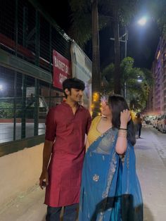 a man and woman walking down the street at night