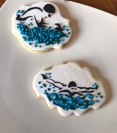 two decorated cookies sitting on top of a white plate