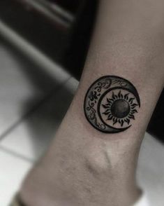 a black and white photo of a person's foot with a sun and moon tattoo on it