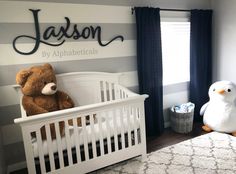 a baby's room with striped walls and white crib, teddy bear and penguin