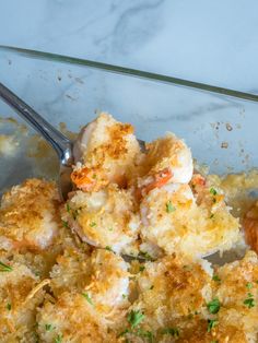 a glass dish filled with shrimp and bread crumbs, garnished with parsley