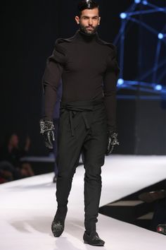 A Futuristic Construction; This high collar jacket is rendered in black cotton jersey. The defining feature of the jacket comes in the form of a 3-D sculpted wave extending from the shoulders all the way down to the sleeves. It is punctuated with a metal zipper closure at the front. Think of a straight leg or draped trouser, as this versatile jacket partners perfectly with multiple looks. #gauravgupta#ggman#runwayshow#menscouture Futuristic Construction, High Collar Jacket, Versatile Jacket, Collar Jacket, Way Down, Metal Zipper, High Collar, Black Cotton