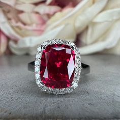 a close up of a ring with a red stone in the center and white diamonds around it