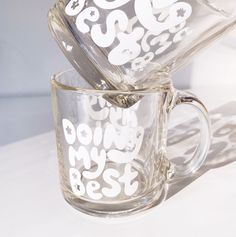 two clear coffee mugs sitting on top of a white table next to each other