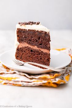 a slice of chocolate cake on a white plate with a fork and napkin next to it