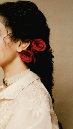 a woman with long black hair and red flowers in her hair is looking off to the side