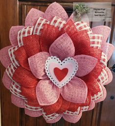 a red and white wreath with a heart on it's front door hanger