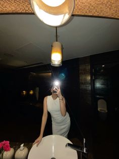 a woman taking a selfie in front of a mirror with a light on it