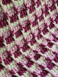 a crocheted blanket is shown with pink and white stripes on the bottom half