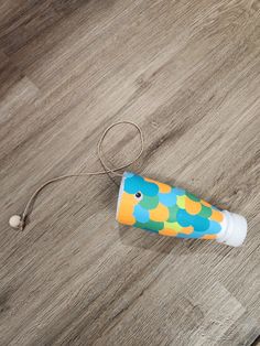 an empty tube sitting on top of a wooden floor next to a toy toothbrush