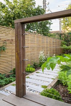 an outdoor garden with wooden fence and green plants in the foreground, surrounded by wood slats