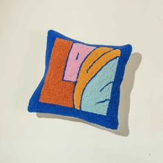 a blue and orange pillow sitting on top of a white wall