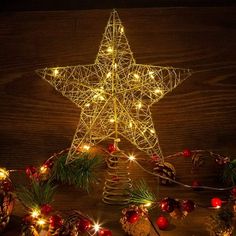 a lighted christmas star surrounded by pine cones and other holiday decorations on a wooden table