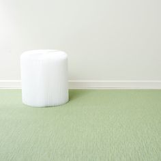 a white stool sitting on top of a green carpeted floor next to a wall