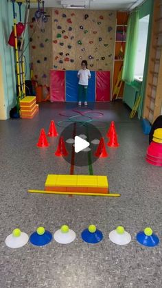 a child is standing in the middle of an indoor play area with plastic cones and obstacles