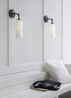 a pair of wall lights mounted on the side of a window sill next to a pillow