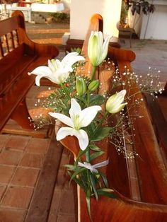 white flowers are in a vase on the pews