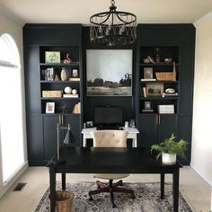 a home office with black bookcases and a chandelier