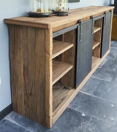 a wooden cabinet with metal doors and drawers on the bottom shelf next to a blue wall