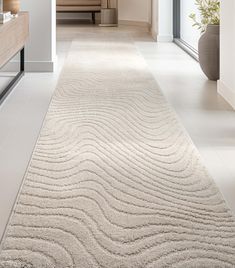 a large white rug with wavy lines on the floor in front of a couch and table