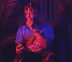 a man with dreadlocks is looking at his cell phone while sitting in a chair