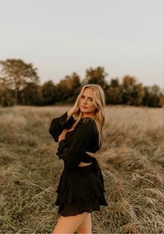 a woman standing in tall grass with her hands on her hips