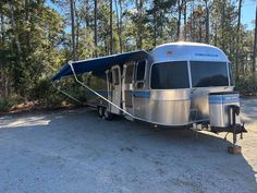 an rv is parked in the middle of a wooded area with its awning open