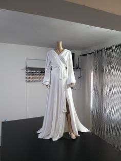 a mannequin dressed in white is standing next to a dress on a stand