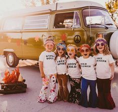 four girls wearing t - shirts with words on them standing in front of a camper van