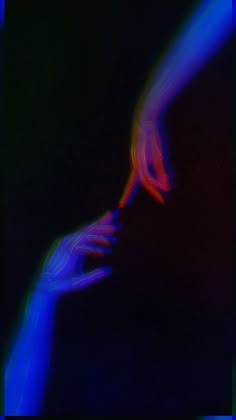 two hands touching each other with colored light in the dark behind them and black background