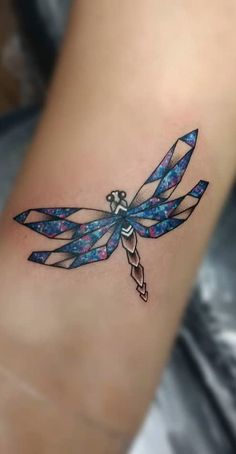 a small blue dragonfly tattoo on the right side of the leg, with an arrow in it's center