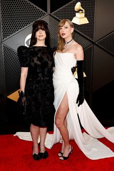 two women standing next to each other on a red carpet