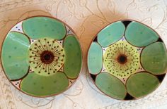 two green bowls sitting on top of a table next to each other with designs on them